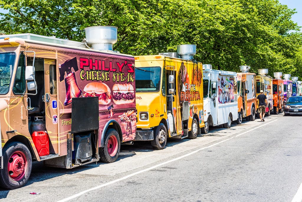 Food trucks lined up on a street during summer