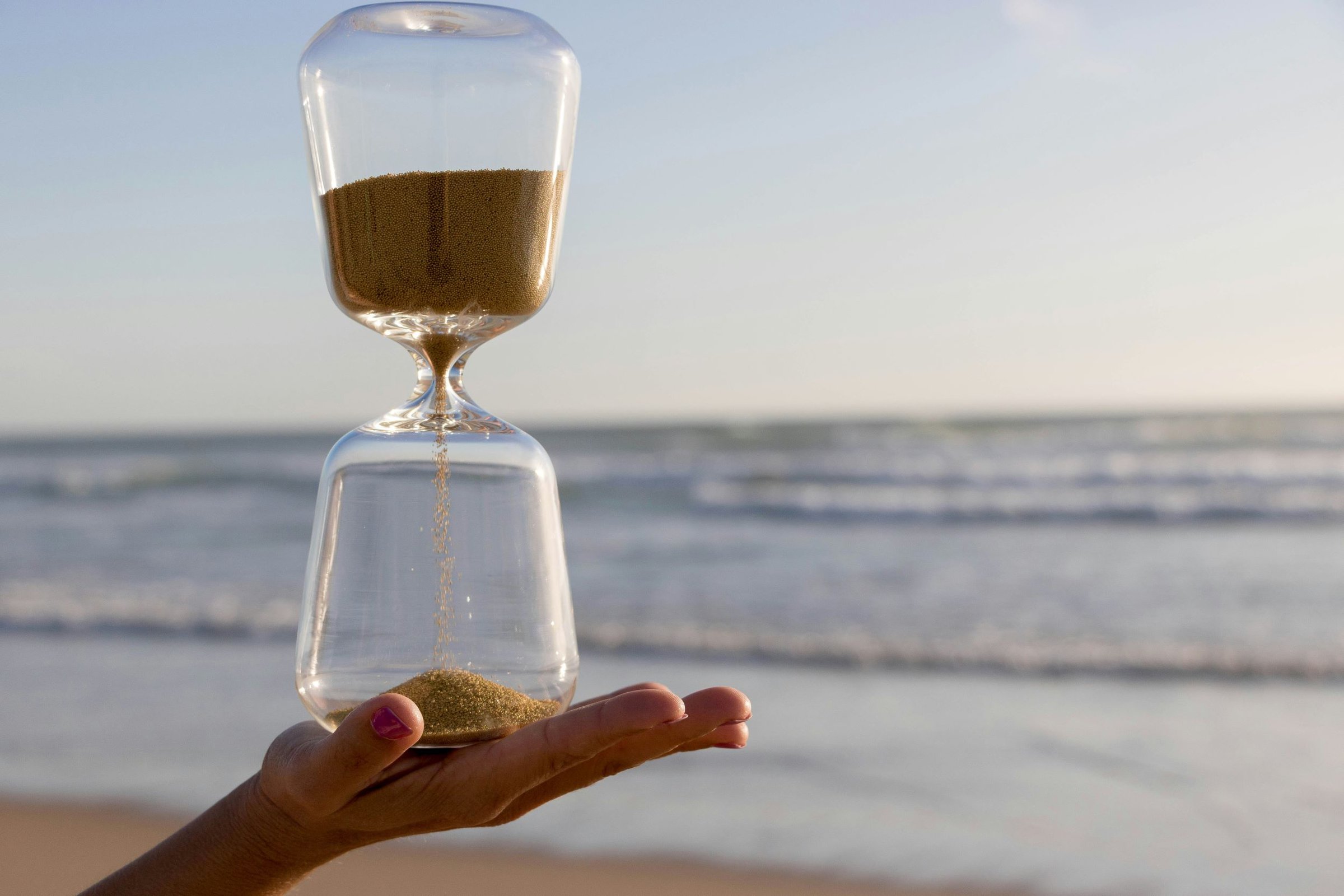 hourglass in a hand on the beach