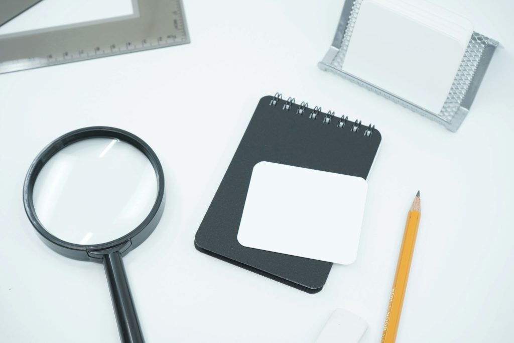 magnifying glass on desk with notebook and pencil