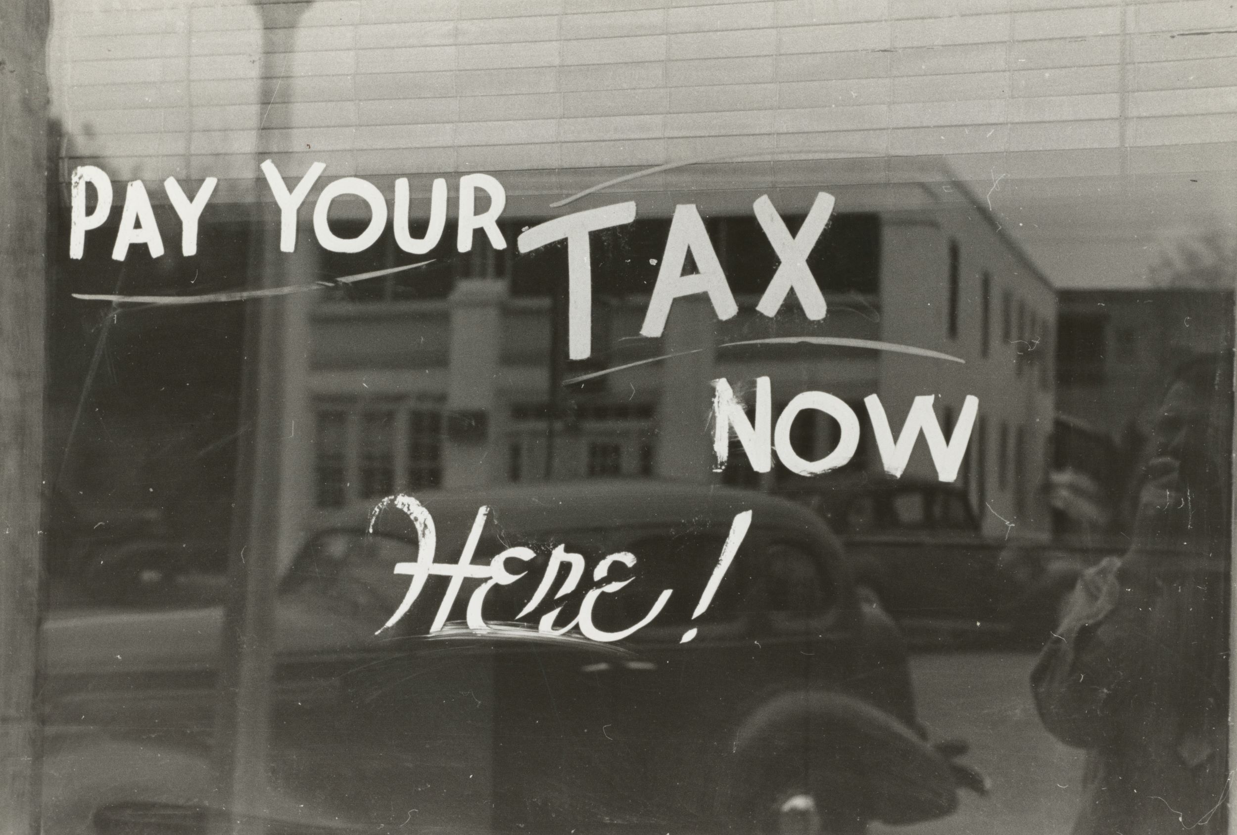 window sign that says "pay your tax now here!"