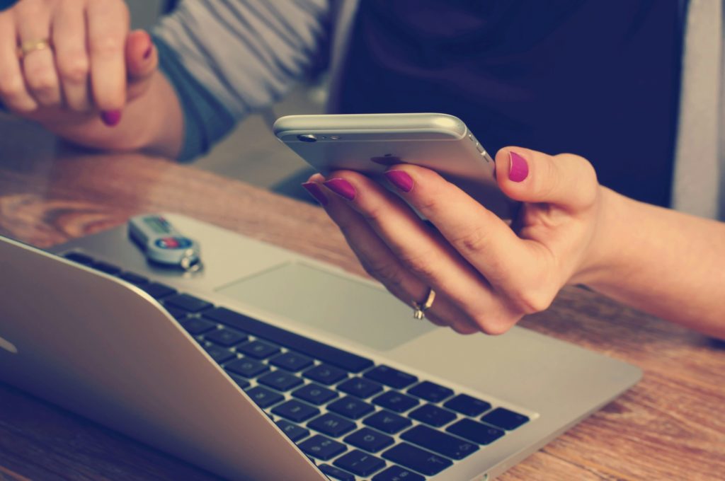 woman holding phone working on a laptop