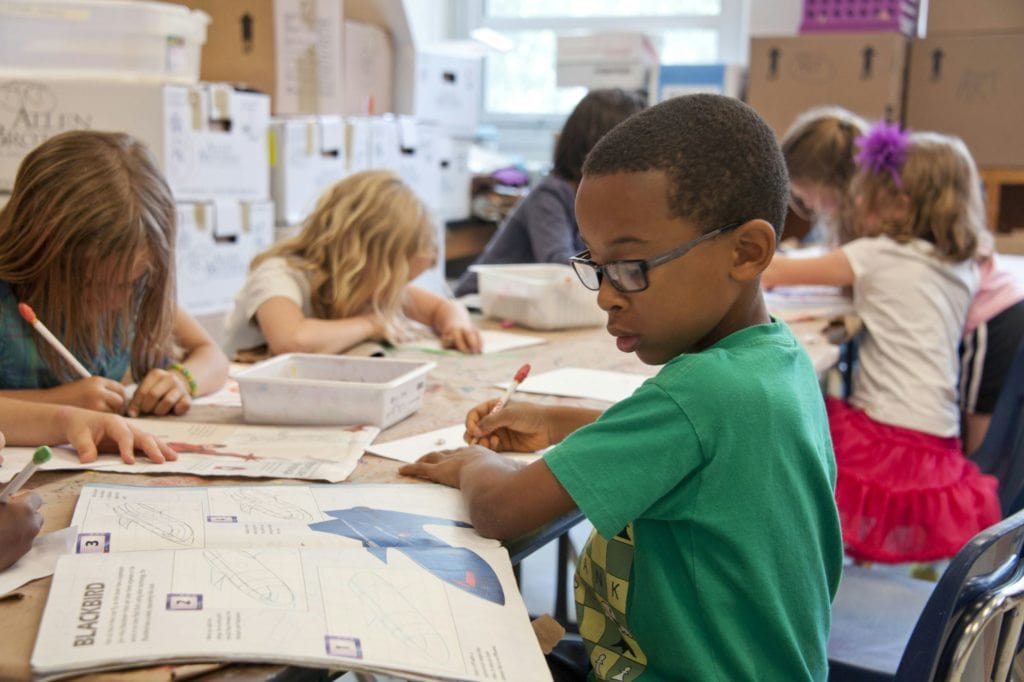 kids drawing in a classroom filled with boxes