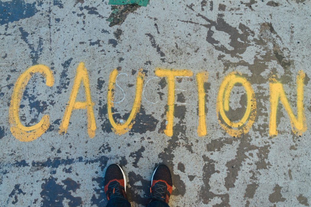 caution sign spray painted on sidewalk