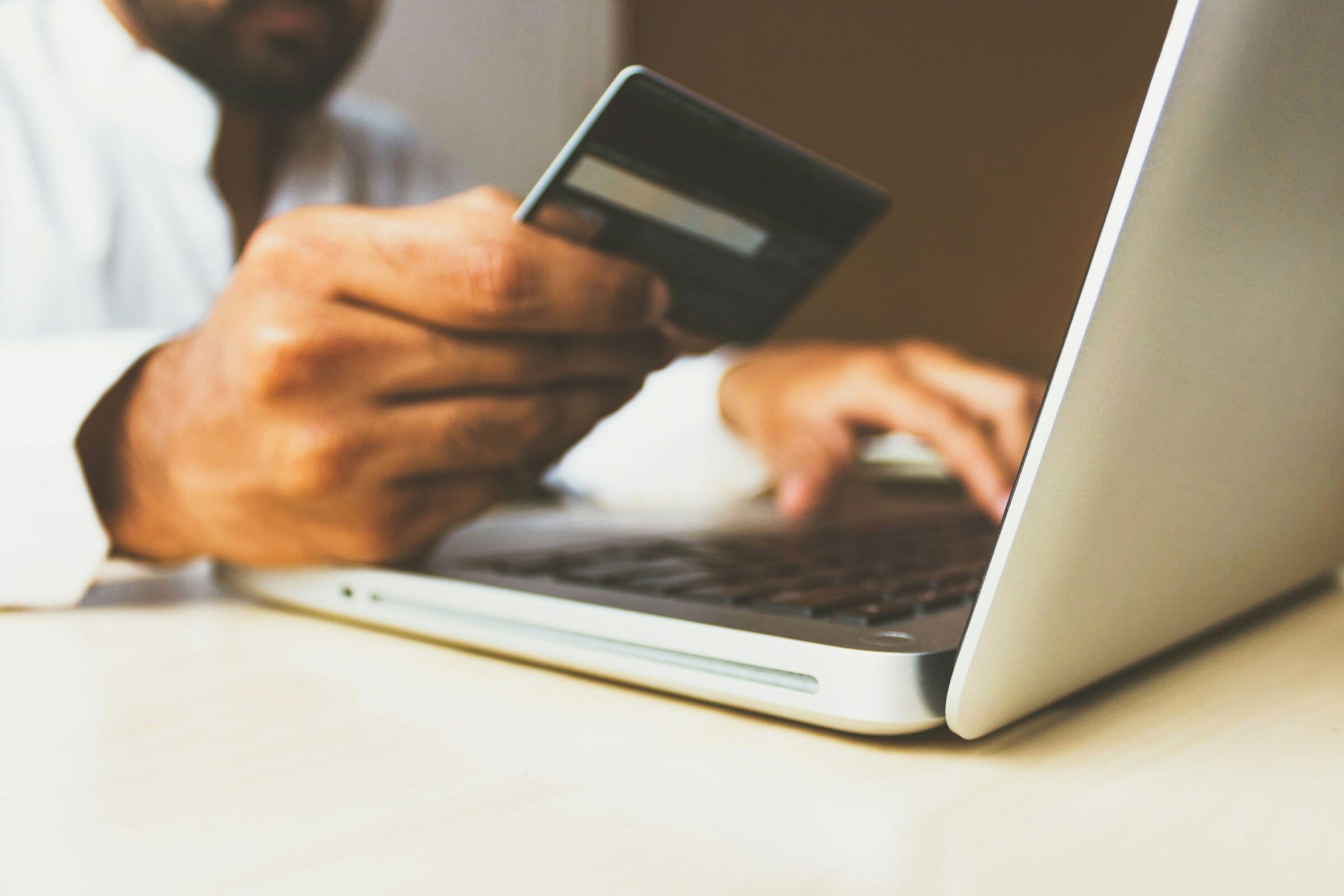 man on laptop holding credit card