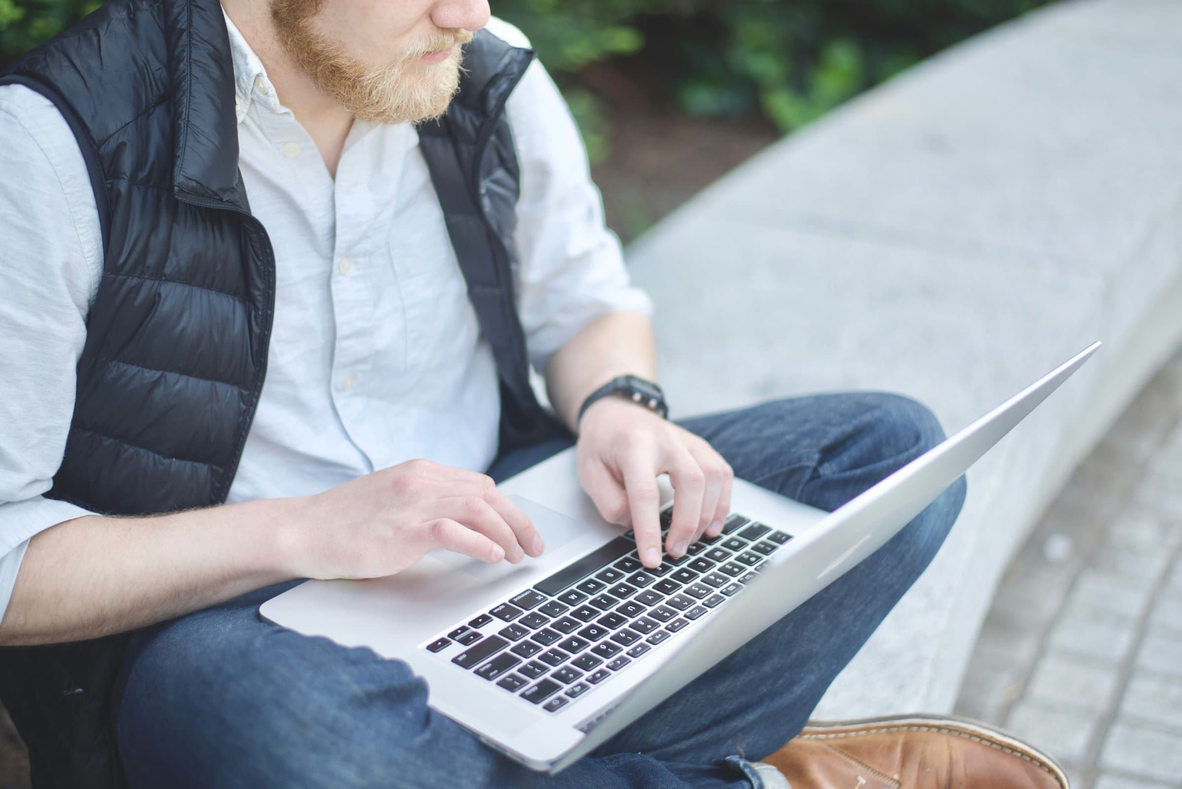 man sitting cross legged typing on a laptop