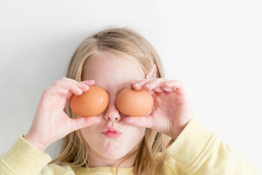 girl holding eggs in front of her eyes