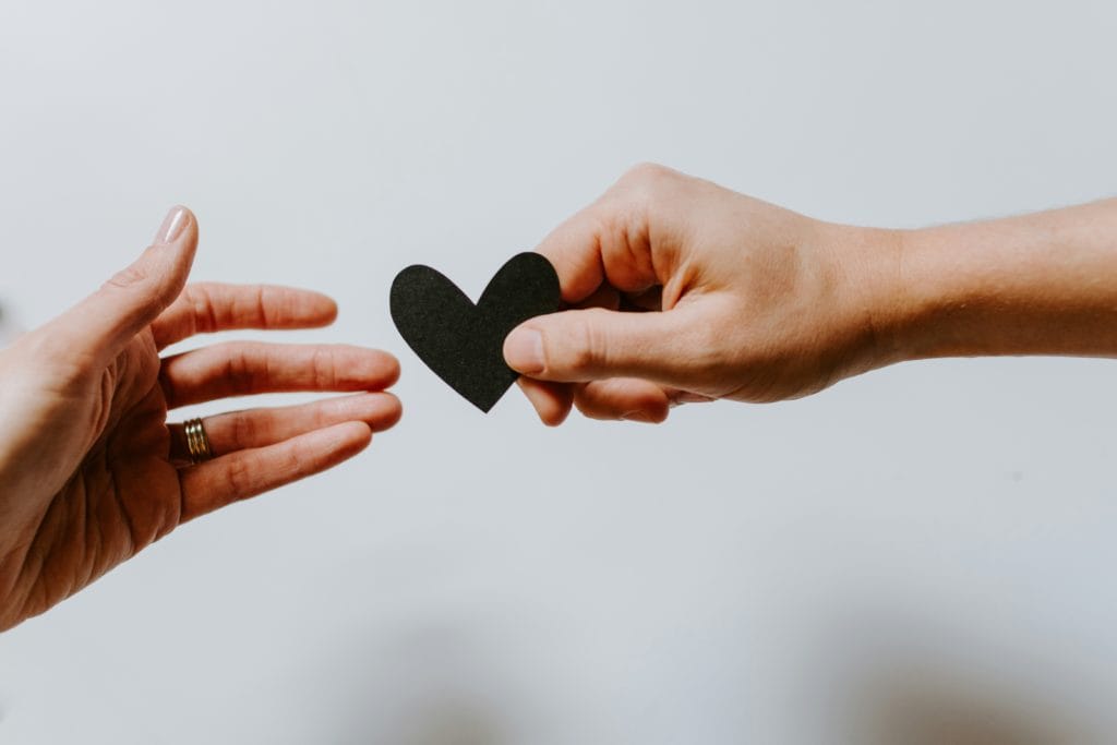 hands handing off a paper heart